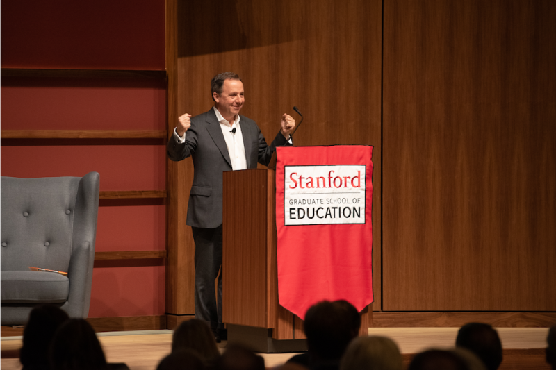 Ron Suskind speaking behind a podium with Stanford GSE logo
