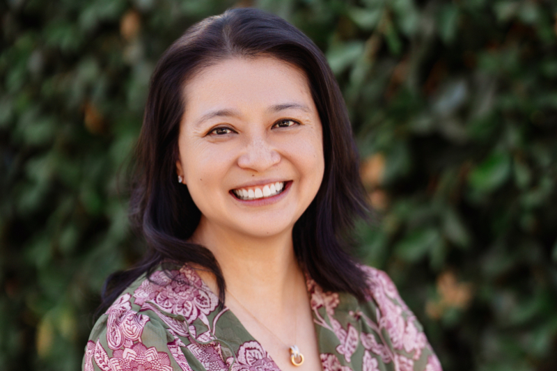 Portrait of Mo Fong, BS ’95, MA '96, in front of greenery.