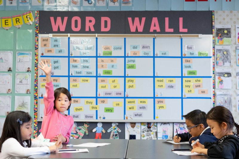 A kindergarten student raises her hand in a dual-language immersion class.