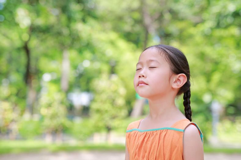 Photo of a young girl taking breaths outdoors