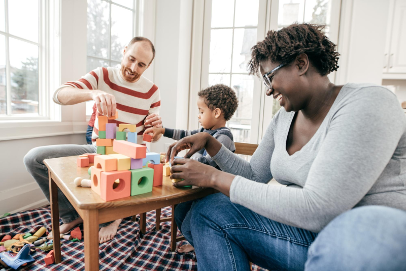 Parents playing with building blocks with a kid in a room
