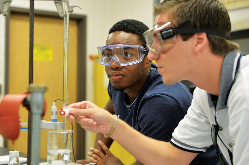 Two students working with science equipment.