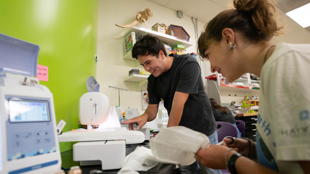 Two students using a piece of equipment in the GSE Makery.