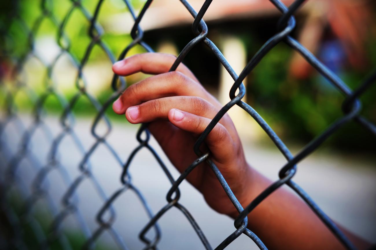 Photo of a hand on a barbed wire fence