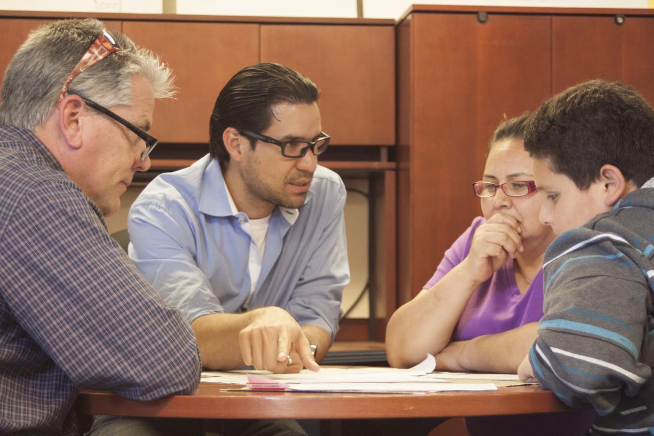 GSE student Efrain Brito, second from left, interprets with Maria Guzman, her son and his teacher, Randy Vail at Pescadero Middle School.
