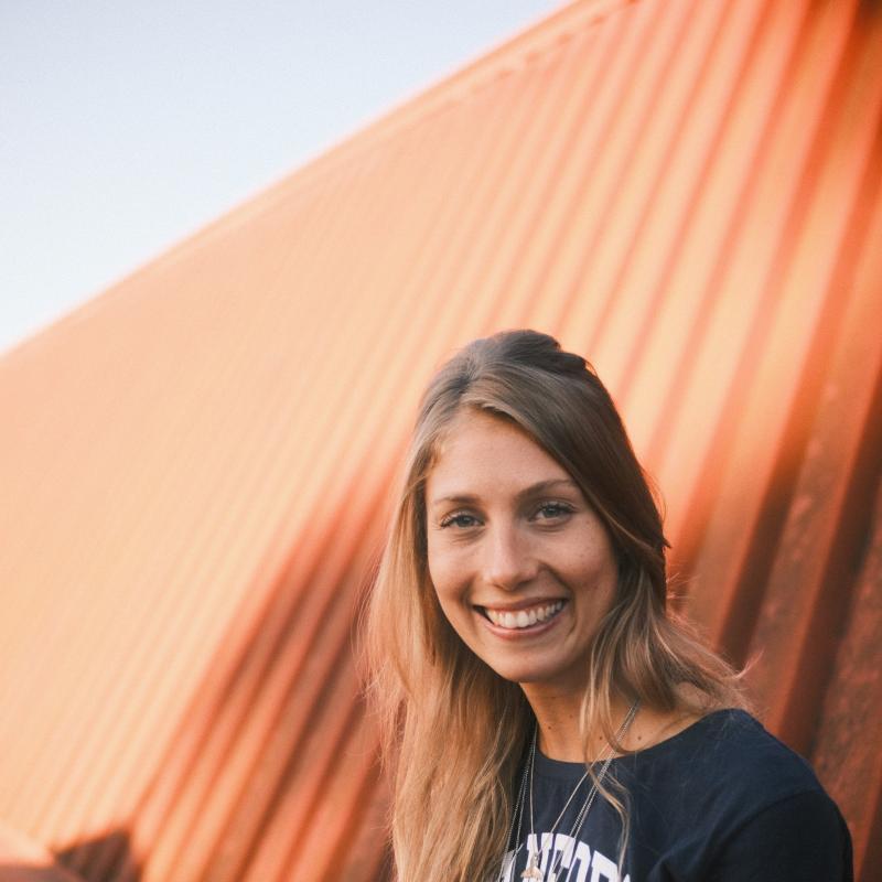 Gabriela Néspoli, smiling, and standing on the CERAS building rooftop patio